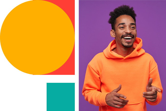 cheerful-young-pretty-bearded-dark-skinned-man-with-curly-black-hair-laughing-happily-and-showing-aside-with-raised-forefingers-standing-against-purple-in-casual-sporty-wear